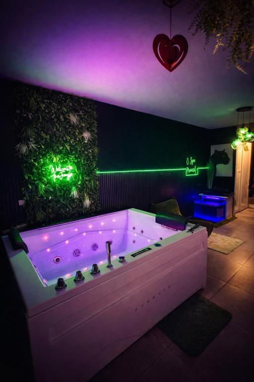 a bath tub with purple lights in a room at Ô Spa Privatif - Luxury Suite - JACUZZI-SAUNA-NETFLIX-FISHSPA-SERVIETTES-PEIGNOIRS-SANDALES-CAFE in Morlanwelz-Mariemont
