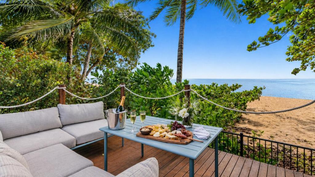a table with a plate of food on top of a patio at Sandveil Absolute Beachfront Access House in Trinity Beach