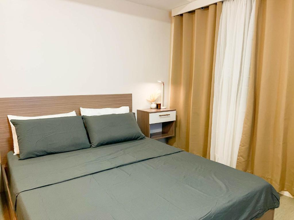 a bedroom with a bed with blue sheets and a window at Be Residences Studio in Cebu City