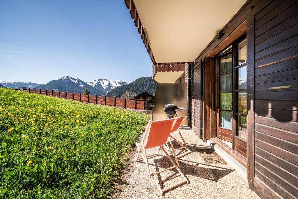 a chair on the porch of a house with mountains at Alpine ski apartment - Petit Chatel in Châtel