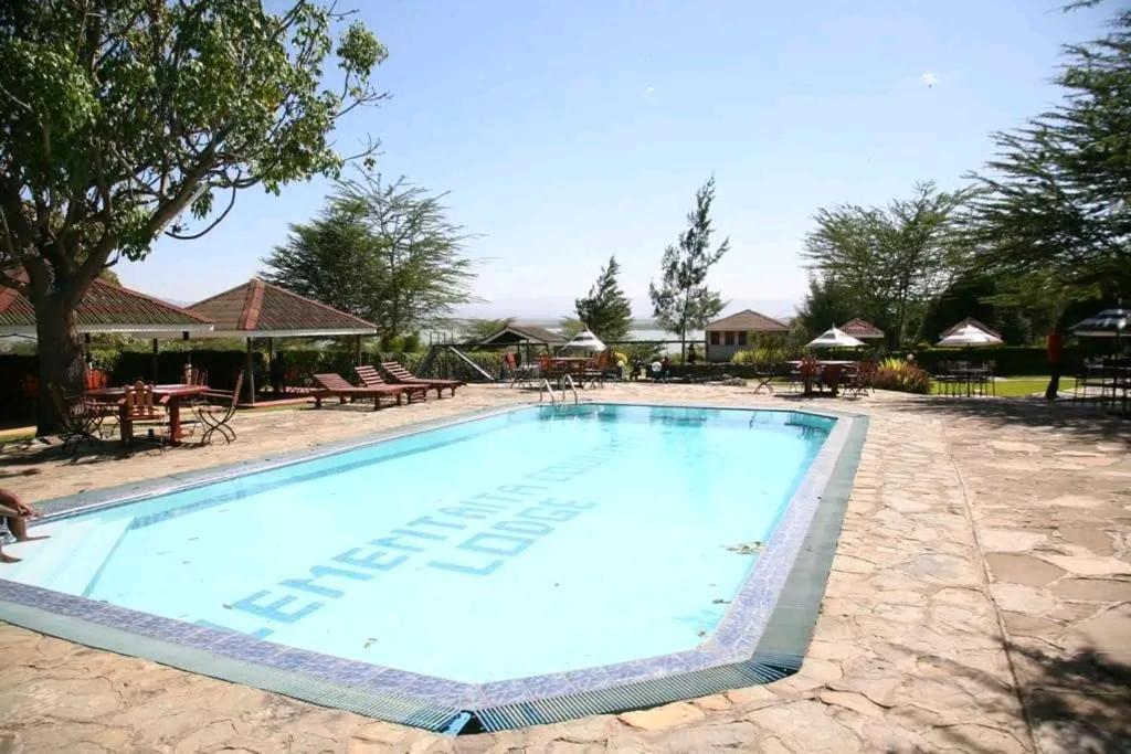ein Schwimmbad in einem Ferienresort mit Tischen und Stühlen in der Unterkunft Seasons Elementaita Country Lodge in Nakuru