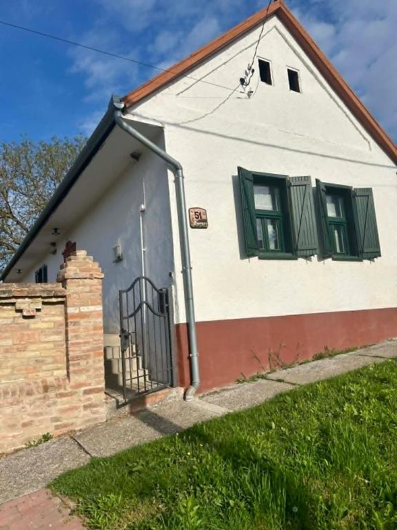 a white house with green windows and a gate at Levendulásház Palkonya in Palkonya