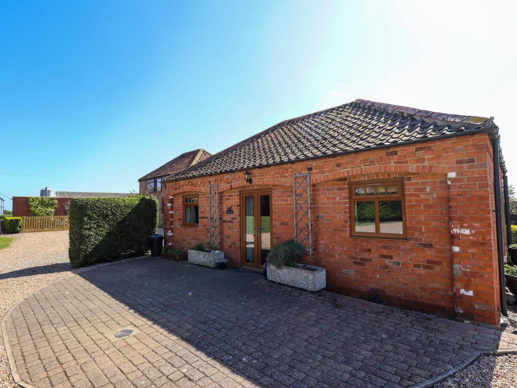 a red brick building with a brick driveway at Kingfisher in Louth