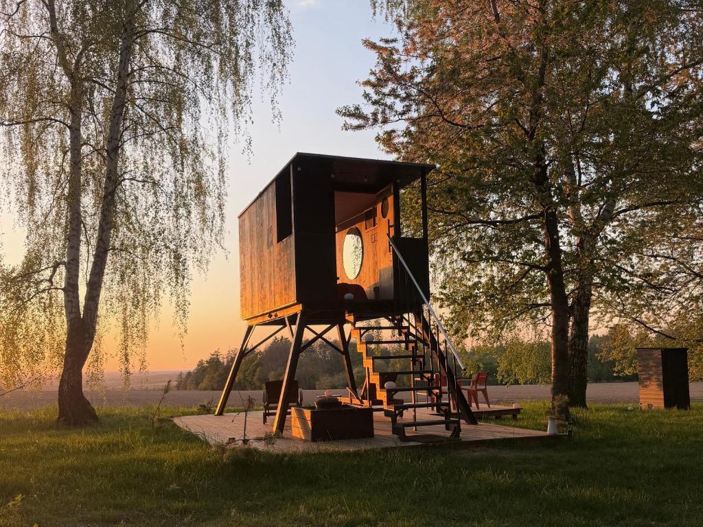 a tree house with a clock on it in a field at Ostrov klidu - posed - sauna in Hradešín