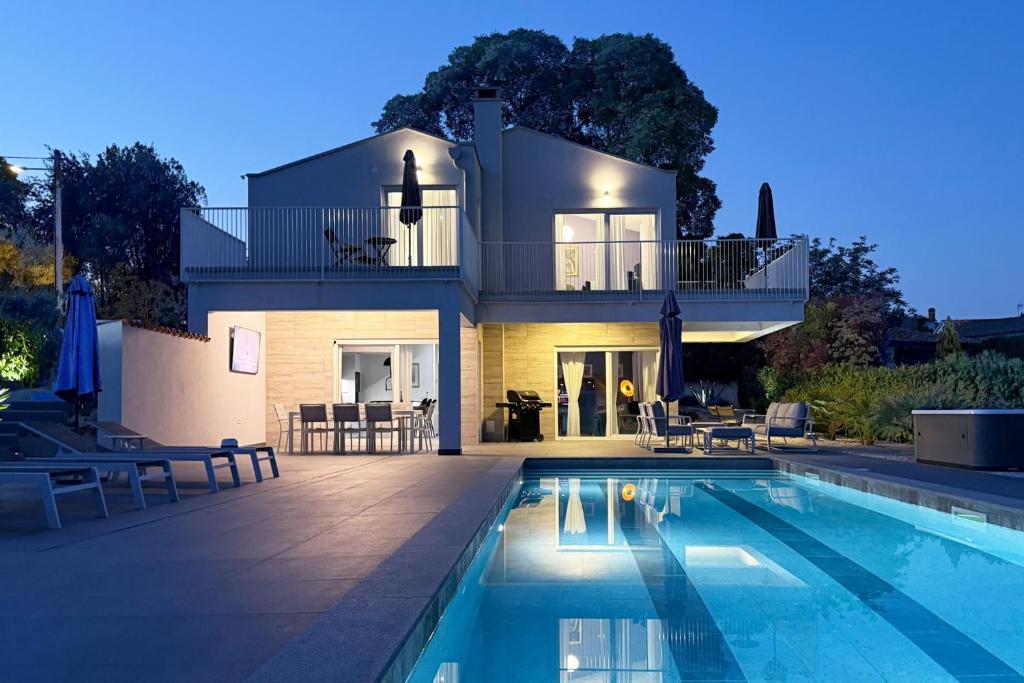 a house with a swimming pool in front of a house at Casa Belladonna by Briskva in Višnjan