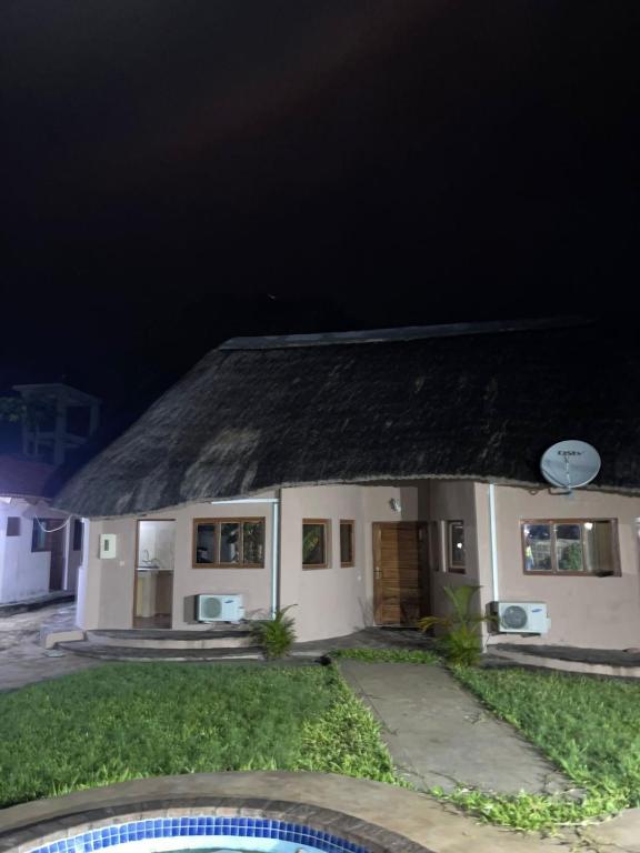 a small white house with a roof at night at The Huts in Vila Praia Do Bilene