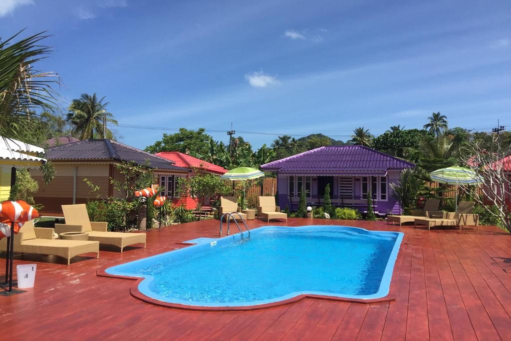 a swimming pool in a yard with chairs and a house at Phetmanee Resort in Ko Yao Noi