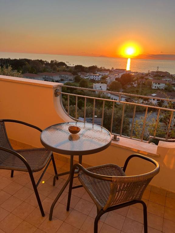 a table and chairs on a balcony with a sunset at Hotel La Giara in Zambrone
