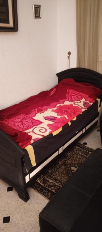 a bedroom with a bed with a red blanket at Chambre single de Luxe in Kasbah