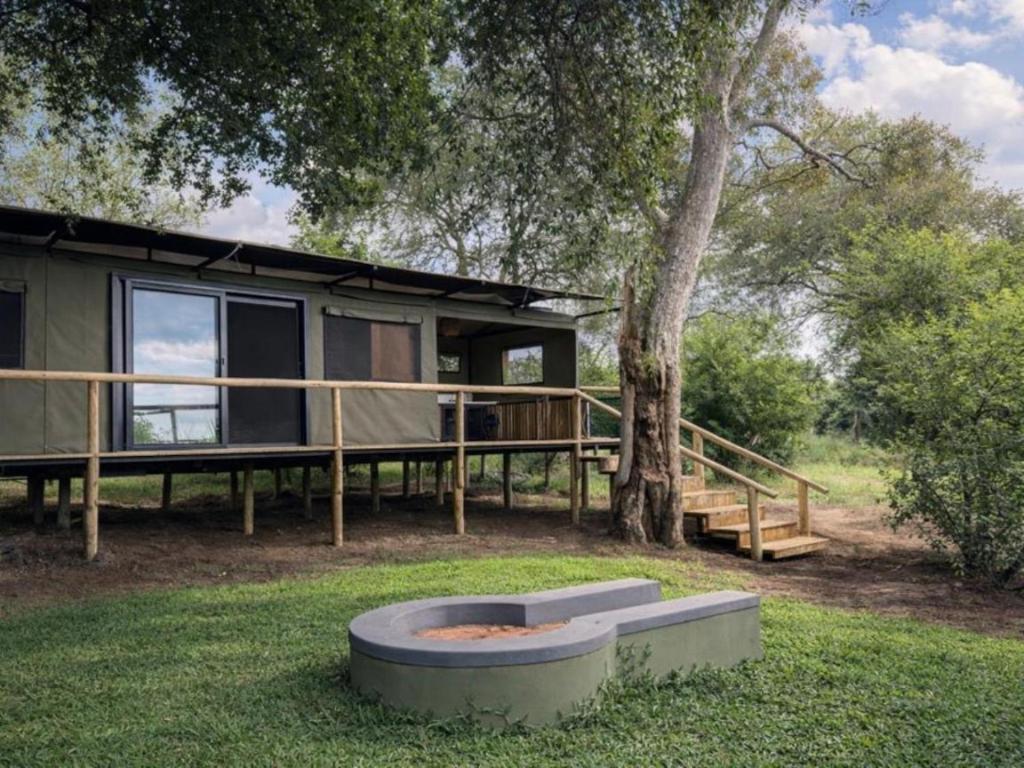 a cabin in the woods with a tree at Buffalo Tented Camps in Mahango