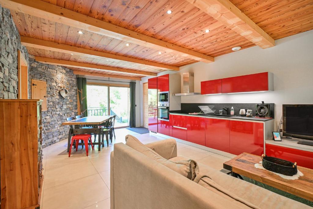 a living room with a couch and a kitchen with red cabinets at Appartement Alice - Dans chalet in Les Villards-sur-Thônes