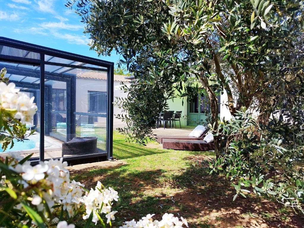 a glass house with a tree in the yard at Villa de l'Olivier in Aytré