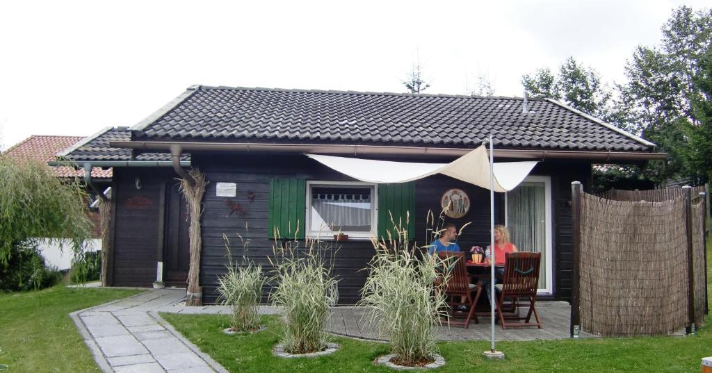 una pareja sentada en una mesa frente a una casa en Ferienhaus Altenstrasser, en Philippsreut