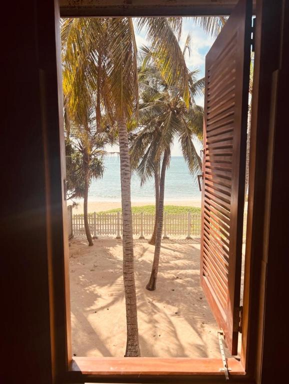 a window view of a beach with palm trees at CocoBaru - Private Beachfront Entire Villa in Marawila
