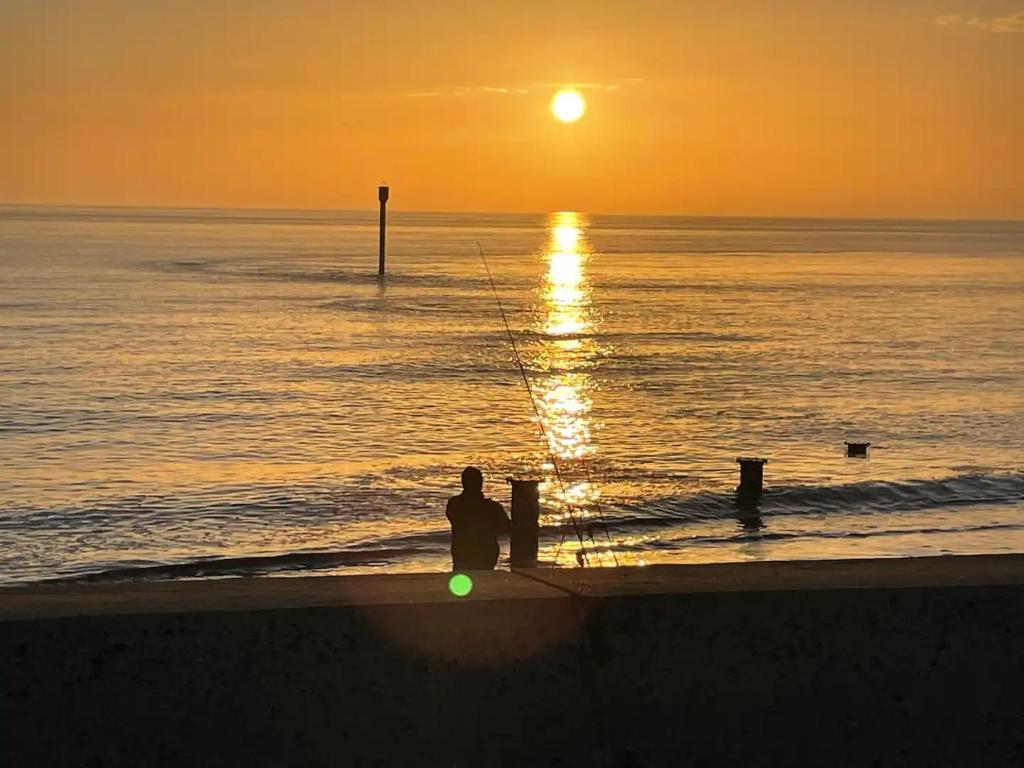 a man sitting on the beach watching the sunset at my happy place caravan in Trusthorpe