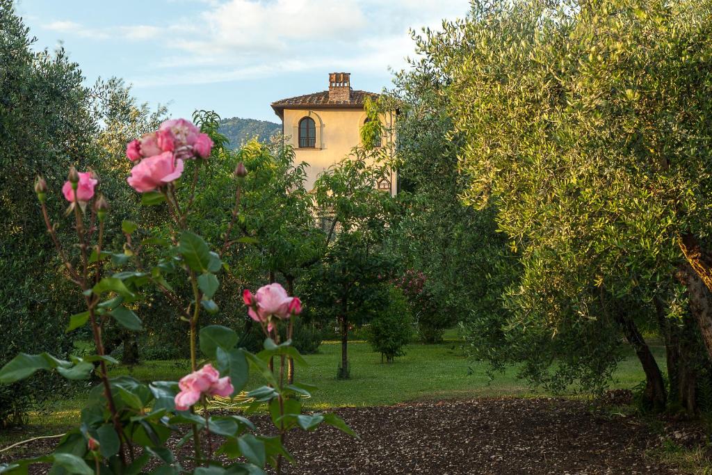 uma casa no fundo com rosas rosas no primeiro plano em Villa Il Paradisino em Sesto Fiorentino