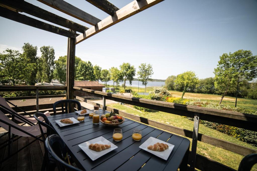 a table with food on top of a balcony with a view at Le Bellevue, 50m lac, piscine, parking, wifi, baignade surveillée in Aureilhan