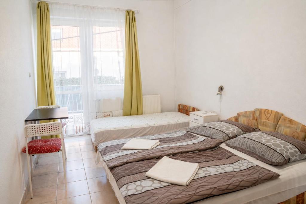 a bedroom with two beds and a window at Klassz Apartmanház in Balatonfüred