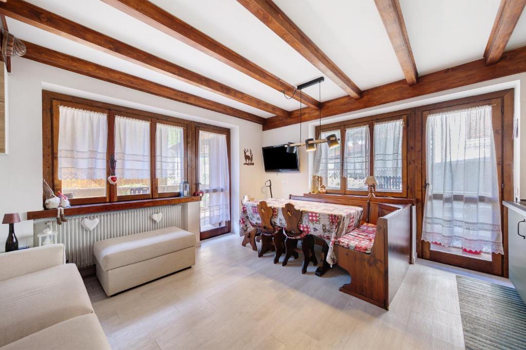 a living room with a table and chairs and windows at Casetta del Caregon a Vinigo in Vodo Cadore