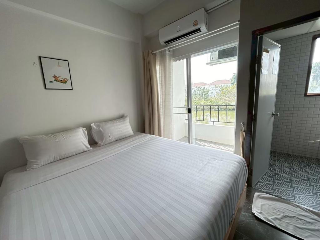 ein weißes Bett in einem Zimmer mit Fenster in der Unterkunft Comfy hotels คอมฟี่โฮเทล in Suvarnabhumi Airport