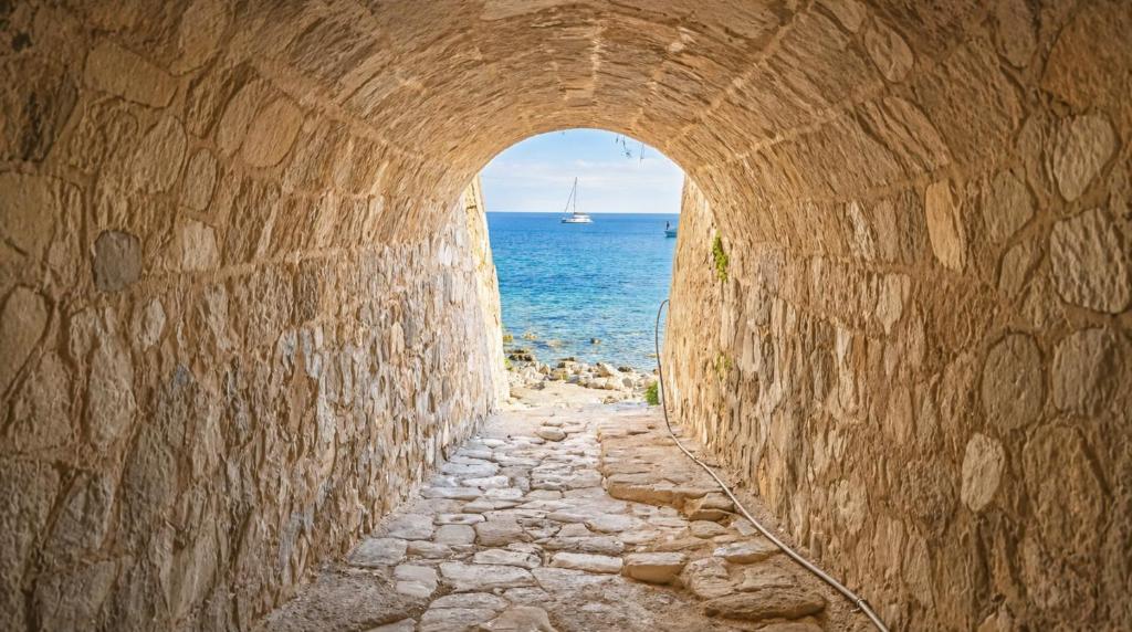 a tunnel leading to the ocean with a sail boat in the distance at casa del sole in Taormina