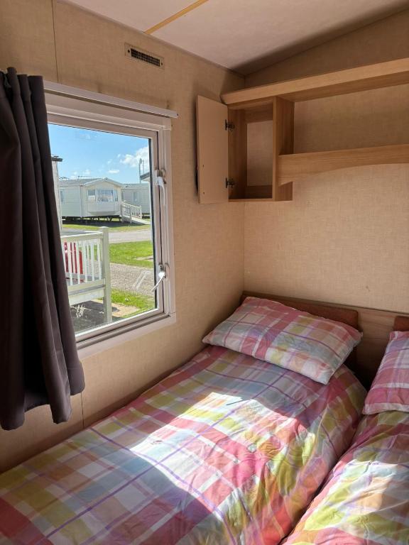 a small bedroom with a bed and a window at 6Berth Caravan-Wheelchair Accessible-Pet Friendly in Skegness