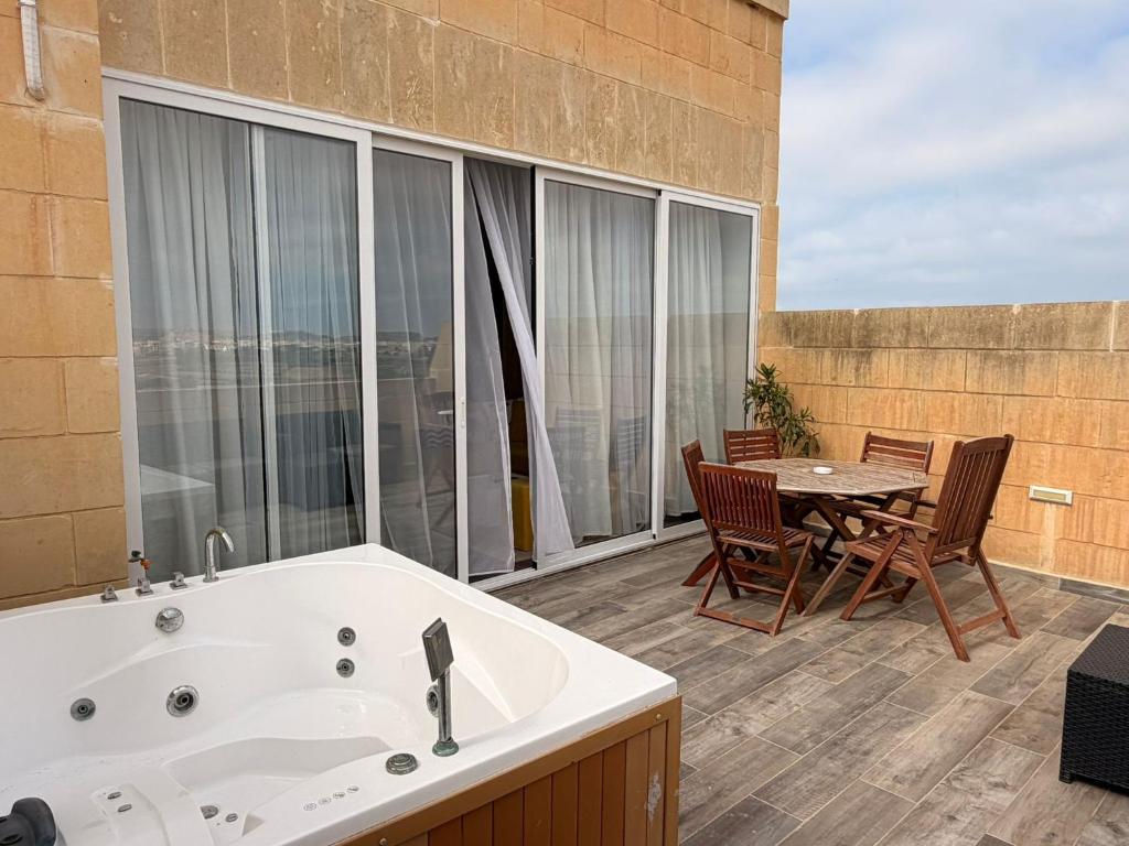 a bathroom with a tub and a table and chairs at De Rock Penthouse in Sannat