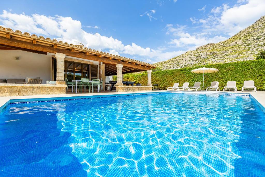 a large swimming pool with chairs and an umbrella at Villa Cal Peso in Port de Pollensa