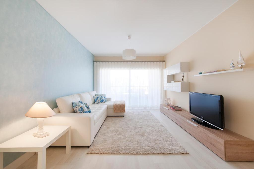 sala de estar con sofá blanco y TV en Rocha Blue Sea Apartment, en Portimão