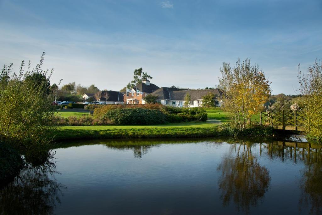 a view of a pond with houses in the background at Sandford Springs Hotel and Golf Club in Kingsclere