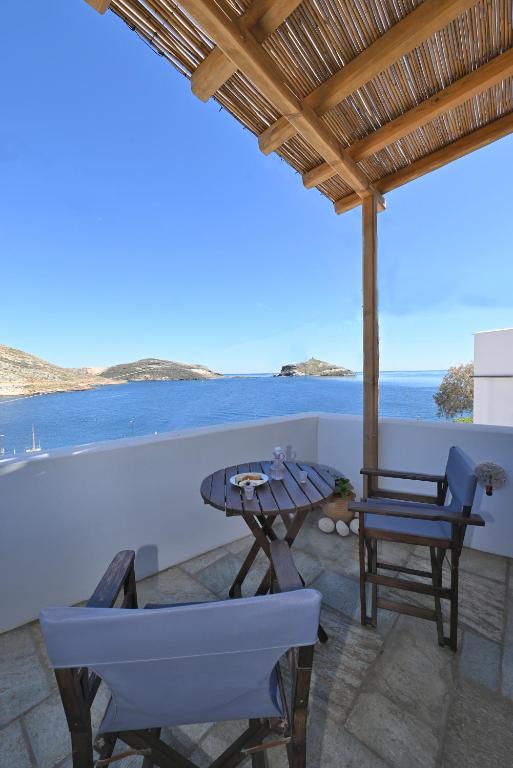 a patio with a table and chairs and a view of the ocean at Molos Tinos Cycladic house in Panormos