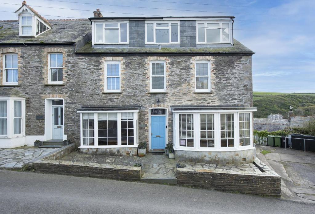 a large stone house with a blue door at Trethoway in Port Isaac