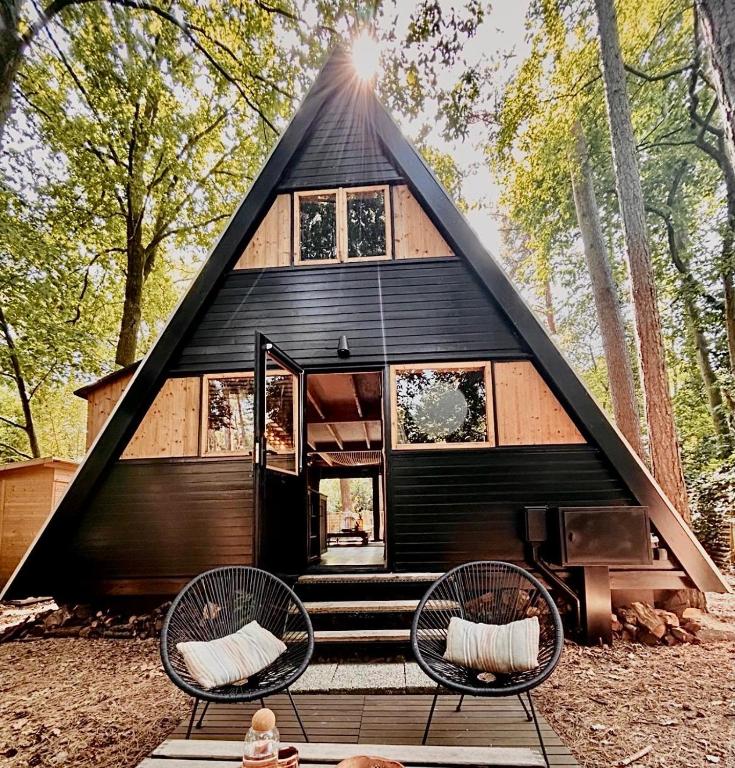 a black house with a triangular roof in the woods at Het Dubbele Punthuisje in Lanaken