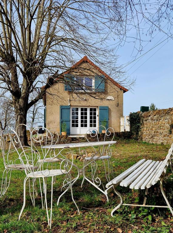 a table and benches in front of a house at A La Bruyère in Saint-Martin-du-Lac