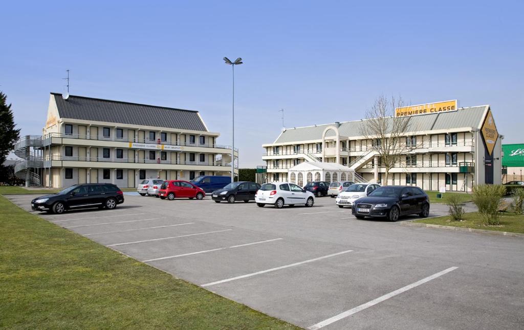 un estacionamiento con autos estacionados frente a un edificio en Premiere Classe Amiens Est - Glisy en Glisy