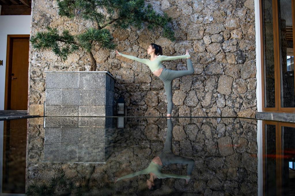 a reflection of a woman in front of a stone wall at PURE Hotel Lijiang in Lijiang