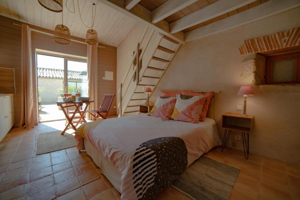 a bedroom with a bed and a staircase and a table at Tamaris in La Jarrie