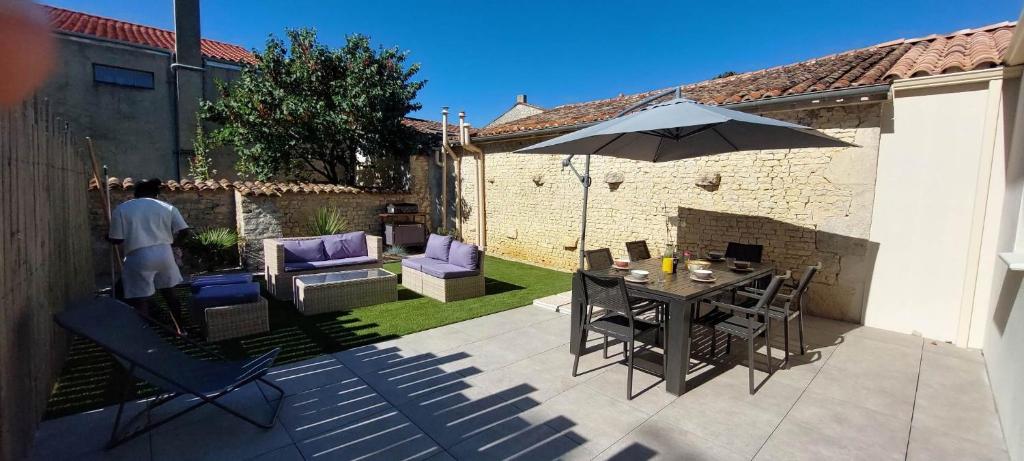 a man standing on a patio with a table and an umbrella at Trémière et cabane in La Jarrie