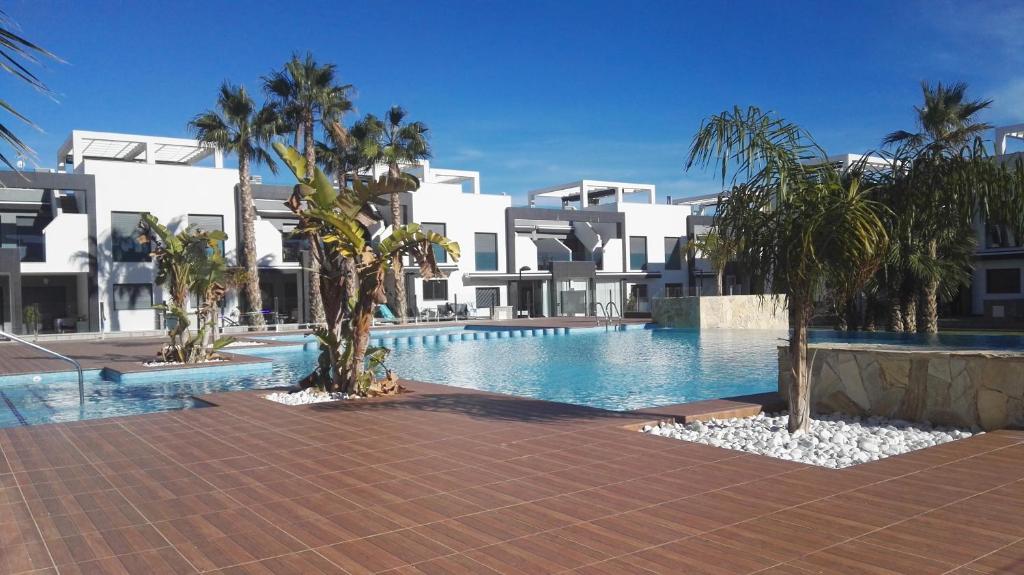 una piscina con palmeras frente a un edificio en Oasis Beach Gabriel, en Orihuela Costa