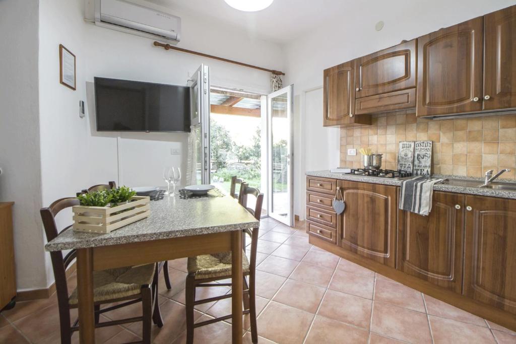una cocina con armarios de madera y una mesa con sillas. en Casa Vacanze Cau - Viale Europa, en Alghero
