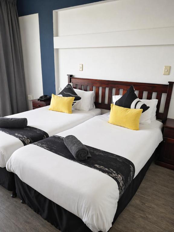 two beds in a hotel room with yellow and black pillows at Hoedjiesbaai Hotel in Saldanha