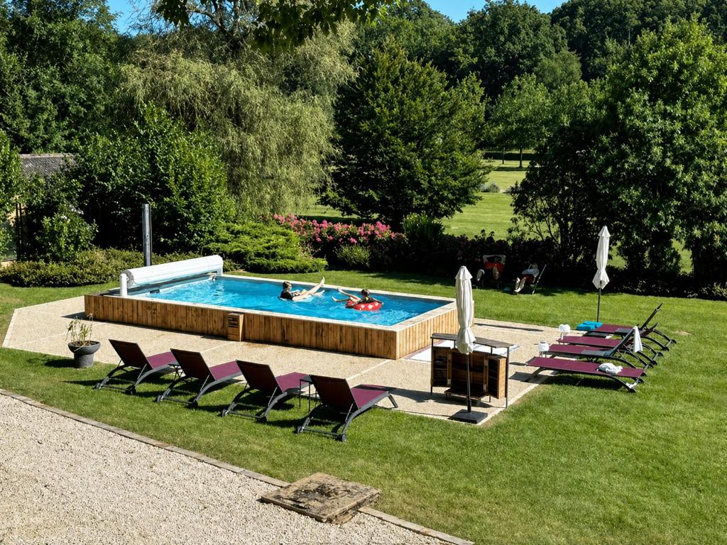 a pool in a yard with chairs and a person in it at Domaine de Thironne Lac & Nature in Montigny-le-Chartif