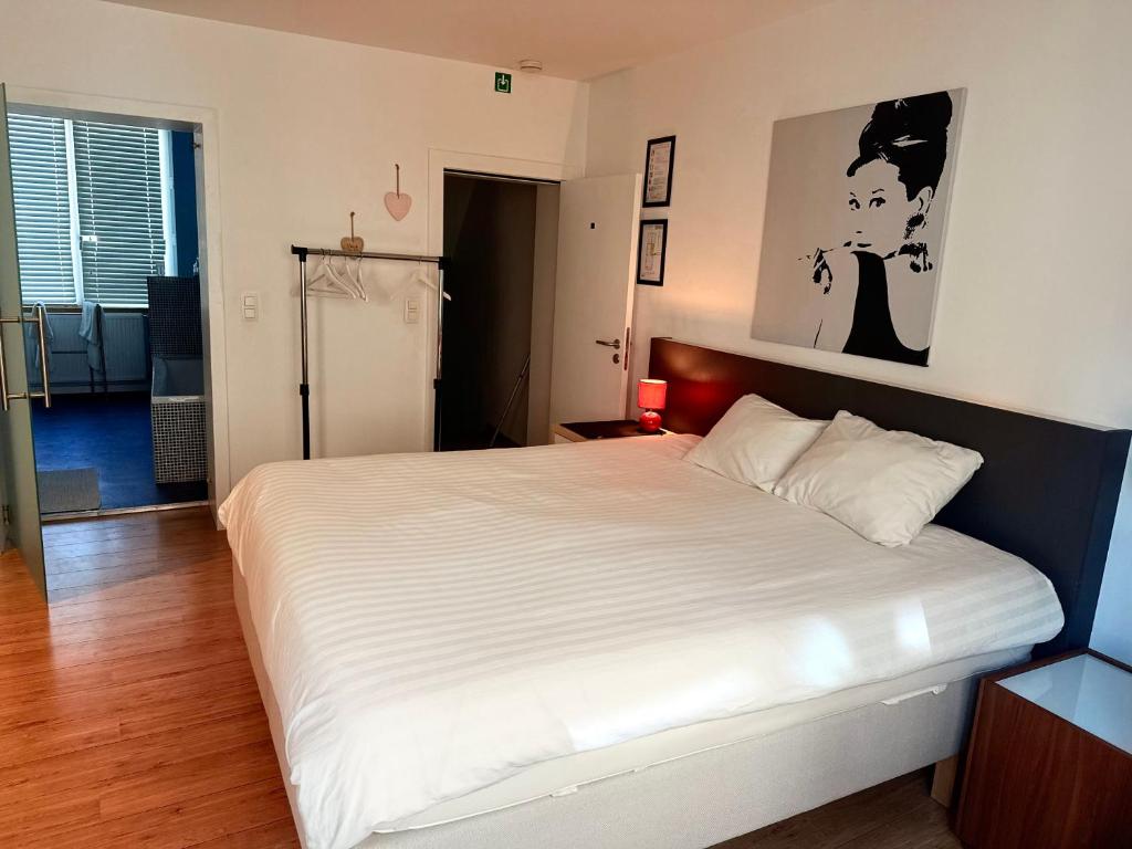 a bedroom with a large white bed in a room at Logies Zen aan Zee in Ostend