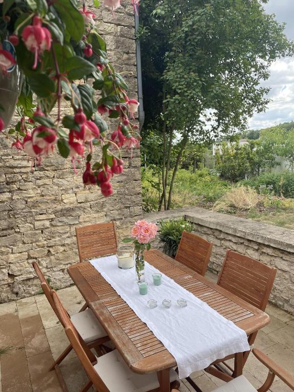 a wooden table with chairs and flowers on a patio at Le Clos des Erables in Dijon
