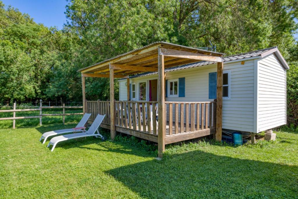 a small white house with a porch and two chairs at Mon Gite En Camargue in Le Cailar
