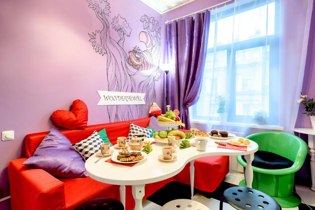 una sala de estar con un sofá rojo y una mesa con comida. en WonderHostel Central, en San Petersburgo