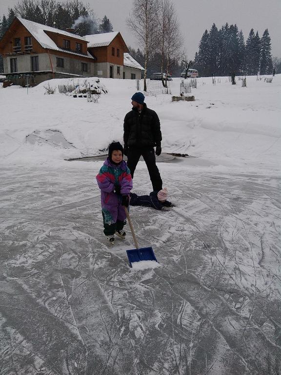 a man and a little girl on the ice at Apartmány Kuřátko in Benecko