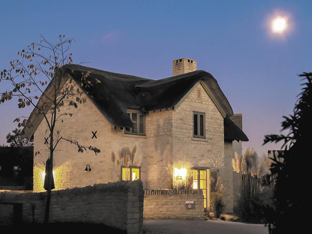 a stone house with the moon in the sky at Moorhens Cottage in Somerford Keynes