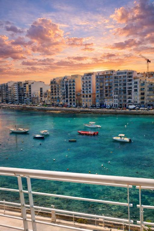 a group of boats in the water near a city at Seafront-Top Location-Close To Shops & Restaurants in St. Julianʼs