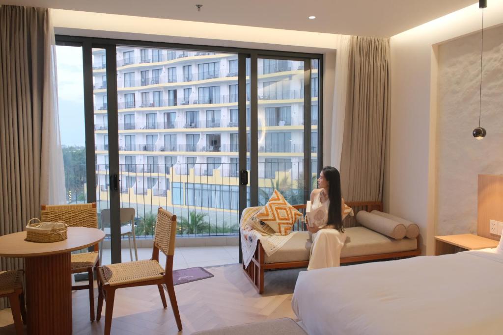 a woman sitting on a couch in a hotel room at Mona Luxe Apartment Hoi An in Hà My Tây (2)